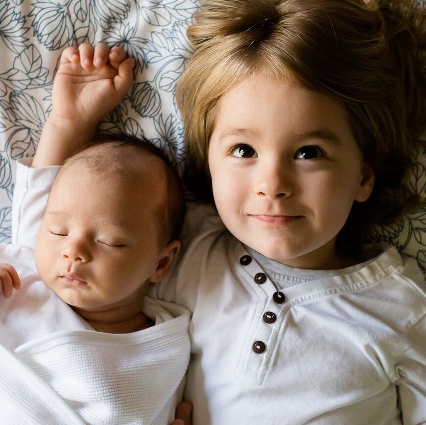 Baby Sleeping Beside Girl on Gray Floral Textile