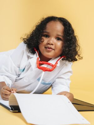 Cute black child imitating doctor while playing in studio